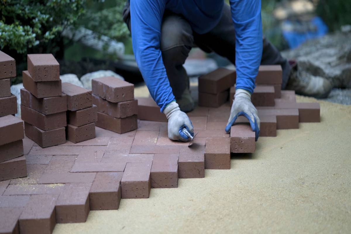 Worker installing bricks for a hardscaping project.